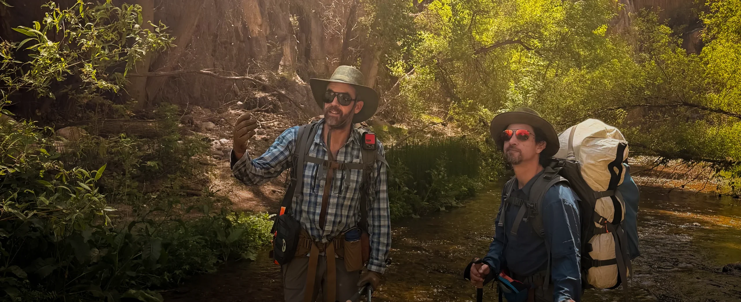 Two Moonflower guides with backpacks beside Aravaipa Creek