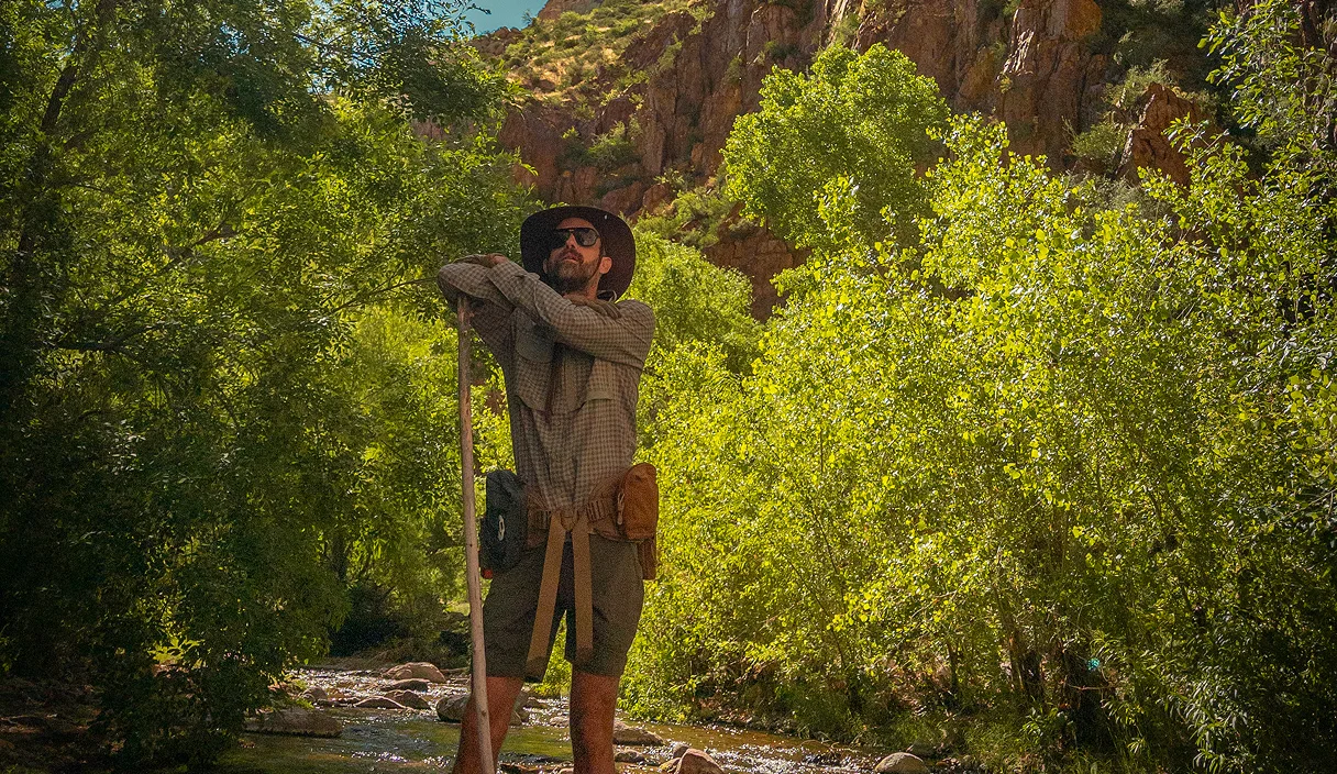 Guide with a trekking pole among cottonwoods along Aravaipa Creek