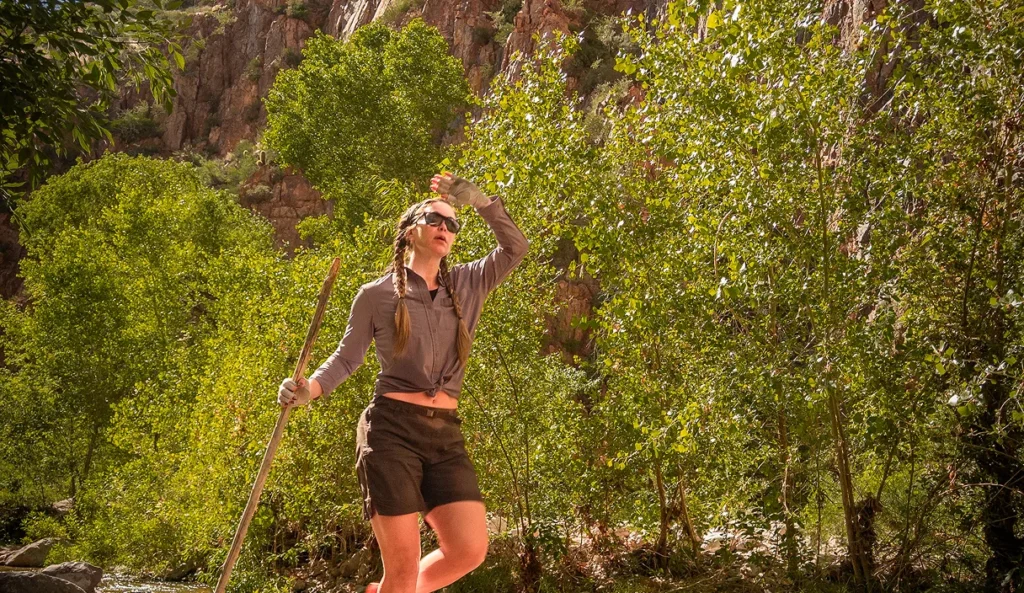 Hiker shading her eyes and looking up at the canyon in Aravaipa