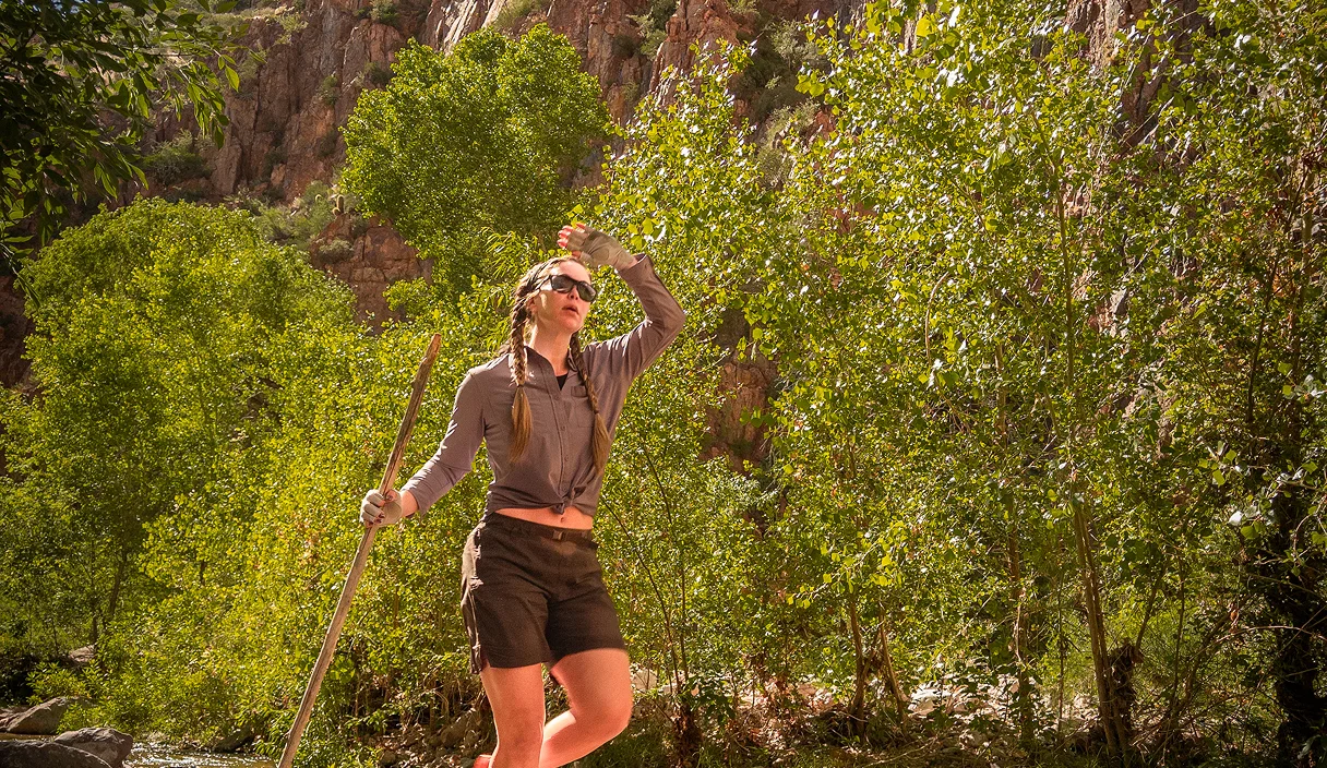 Hiker shading her eyes and looking up at the canyon in Aravaipa