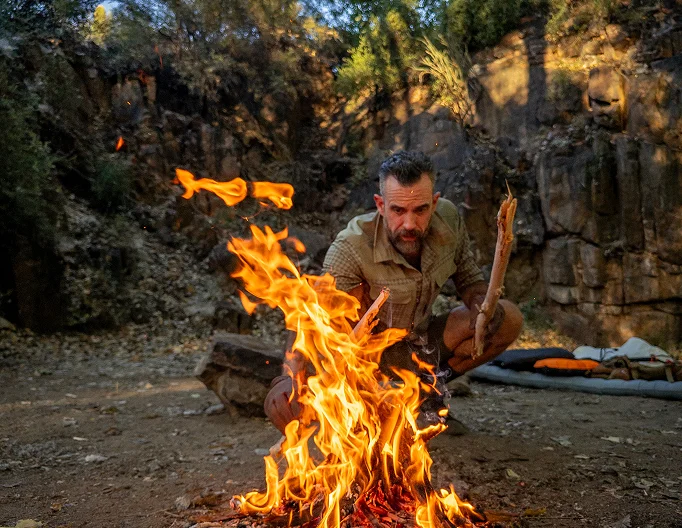 Guide building a campfire at camp in Aravaipa Canyon