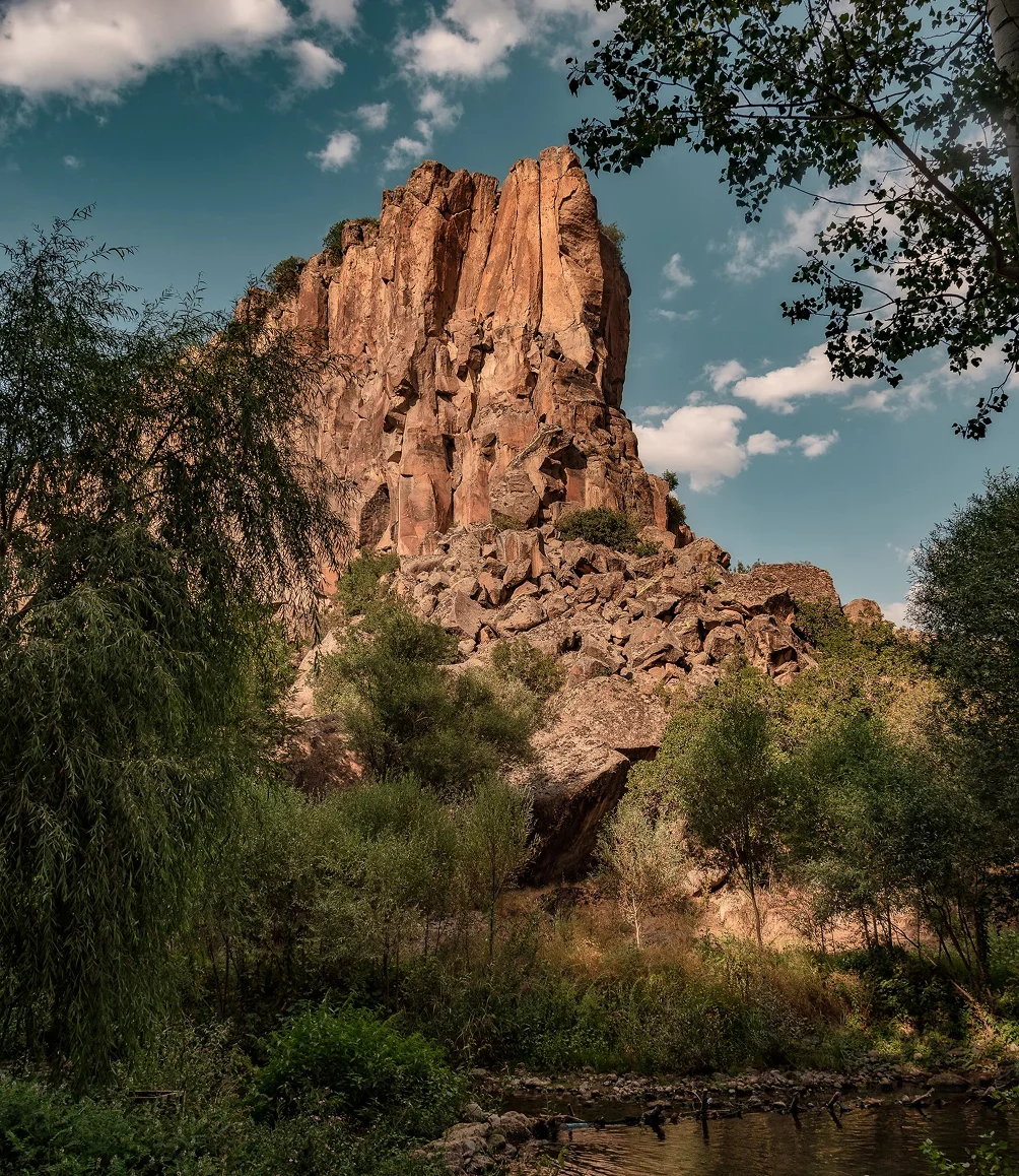 Red rock spire above green trees in Aravaipa Canyon