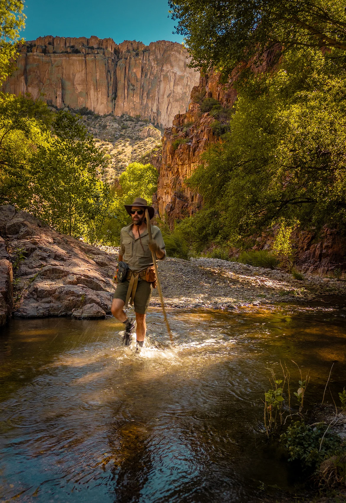 Hiker wading through Aravaipa Creek at golden hour