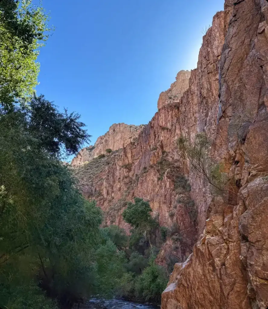 Tall red cliff of Aravaipa Canyon under a clear blue sky